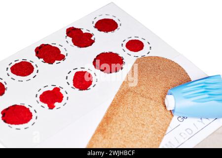 Eine ausgefüllte Blutfleckentestkarte mit Bluttröpfchen für Hormontests Stockfoto