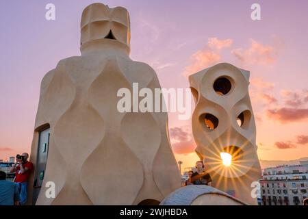 Casa Milà, La Pedrera, Touristen auf dem Dach, Außenterrasse Kamin und Lüftungsschlitz bei Sonnenuntergang, moderne Architektur von Antoni Gaudí, Barcelona, Spanien Stockfoto