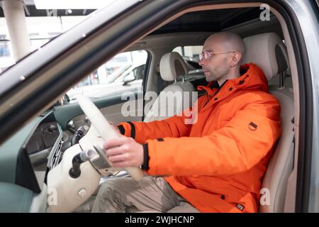 Mann im Auto Fahren Genesis GV60 Elektroauto, Hände am Lenkrad, Innenraum, Cockpit-SUV koreanische Marke Hyundai Unternehmen, Innovation in der Automobilindustrie in Stockfoto