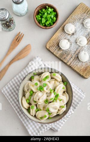 Russische Pelmeni, Knödel mit Fleisch, Butter und Kräutern auf hellem Hintergrund, Blick von oben Stockfoto