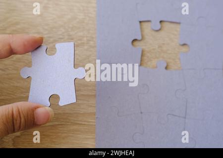 Weibliche Hand hält Papppuzzlespiel, logische Fähigkeiten, Puzzlespiel lösen und Gedächtnisverbesserung, Geschäftskonzept zum Vervollständigen Stockfoto