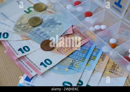 Pillen, Kapseln, Vitamine im Pillbox-Organizer für die Woche, Euro-Banknoten, Konzept der Kontrolle der regelmäßigen Medikamentenaufnahme, Organisation der Medikamentenintak Stockfoto