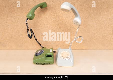 Zwei klassische Telefone mit schwebendem Mobilteil mit Disc Dial, Telefonhörer schweben, fliegt in der Luft, Konzept, Retro Ästhetik 80s, Technologische Transfo Stockfoto