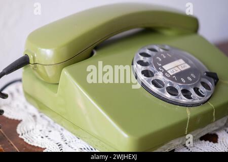 Grünes Drehtelefon mit Disc-Dial, altes Telefon mit Rissen, Verbindung mit Vergangenheit, Anrufe an die Hotline, psychologische Unterstützung Stockfoto