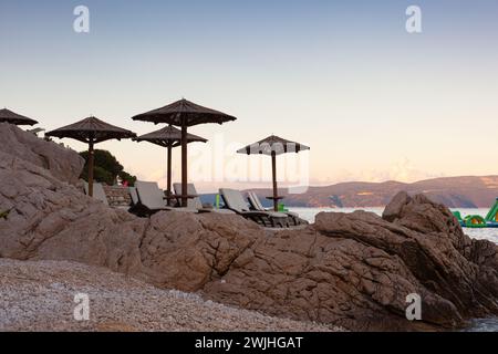 Strohschirme am Strand von Rabac, kroatischer Ferienort an der Kvarner Bucht, direkt südöstlich von Labin in Istrien. Lange ein kleiner Fischerhafen, Rabac Stockfoto