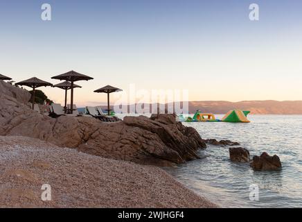 Strohschirme am Strand von Rabac, kroatischer Ferienort an der Kvarner Bucht, direkt südöstlich von Labin in Istrien. Lange ein kleiner Fischerhafen, Rabac Stockfoto