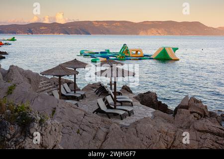 Strohschirme am Strand von Rabac, kroatischer Ferienort an der Kvarner Bucht, direkt südöstlich von Labin in Istrien. Lange ein kleiner Fischerhafen, Rabac Stockfoto