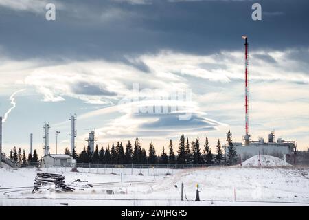 Öl- und Gaskraftwerk mit Flammen und Flammen unter einem dramatischen Winterhimmel in Westkanada. Stockfoto