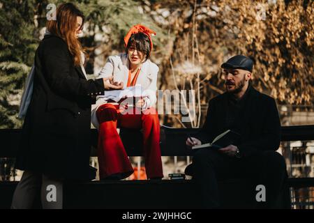Junge Geschäftsleute, die im Freien ein Brainstorming veranstalteten, haben sich in der hektischen Stadt für Erfolg entschieden. Ein vielseitiges Trio arbeitet harmonisch. Stockfoto