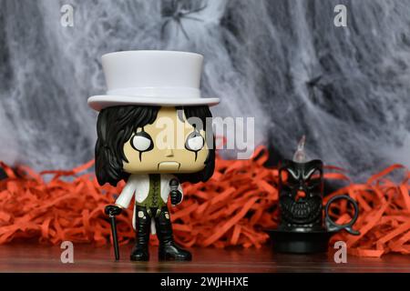 Funko Pop Actionfigur der beliebten Hard-Rock-Sängerin Alice Cooper. Spinnennetz, rotes Dekor, schwarze Kerze, stimmungsvoll, Horror, Halloween, Gothic, dunkel. Stockfoto