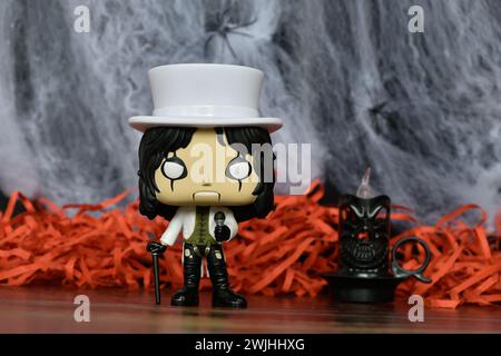 Funko Pop Actionfigur der beliebten Hard-Rock-Sängerin Alice Cooper. Spinnennetz, rotes Dekor, schwarze Kerze, stimmungsvoll, Horror, Halloween, Gothic, dunkel. Stockfoto