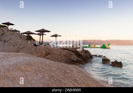 Strohschirme am Strand von Rabac, kroatischer Ferienort an der Kvarner Bucht, direkt südöstlich von Labin in Istrien. Lange ein kleiner Fischerhafen, Rabac Stockfoto