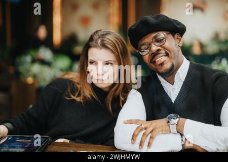 Ein vielseitiges und stilvolles Paar teilt einen Moment in einem Café und vermittelt ein Gefühl von Gesellschaft und modernen Beziehungen in einer ungezwungenen Umgebung. Stockfoto