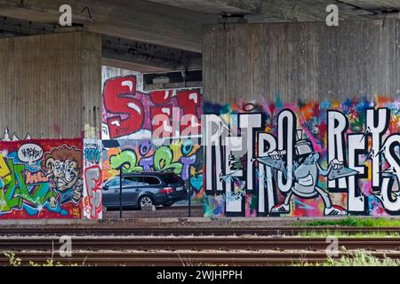 Farbenfrohe Graffiti an einer Betonmauer in einer U-Bahn mit geparkten Autos, Rheinland-Pfalz, Deutschland Stockfoto