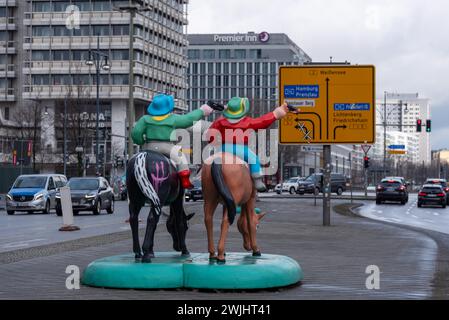 Skulptur von zwei Cowboys auf Pferden, dahinter ein Straßenschild, Berlin Stockfoto