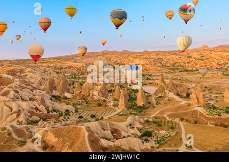 Heißluftballons steigen bei Sonnenaufgang in den kappadokischen Himmel. Versprühen Sie einen zauberhaften Glanz auf die unverwechselbaren Gipfel unter ihnen in Goreme Stockfoto