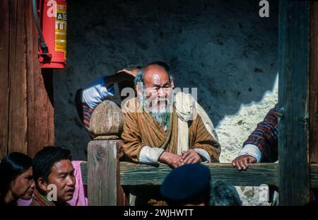 Lokale Zuschauer beim Jakar Dzong Tsechu, einem beliebten jährlichen religiösen und kulturellen Festival, das im Oktober in Jakar Dzong im Bumthang-Tal im Zentrum von Bhutan gefeiert wird. Eine Vielzahl von bunten Maskentänzen werden von Mönchen durchgeführt, die nach präzisen Anweisungen früherer buddhistischer Meister entwickelt werden. Ein älterer Mann aus der Gegend mit einem bärtigen Bart sieht sich die Vorstellung an. Stockfoto