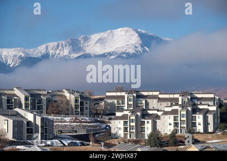 Ein Wintersturm zieht sich über den Pikes Peak in Colorado Springs. Apartments, Stadthäuser und Eigentumswohnungen in den Ausläufern bieten einen wunderschönen Blick auf die Berge. Stockfoto