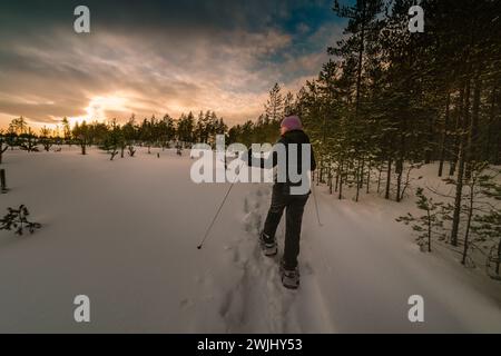 Frauen mittleren Alters in Schneeschuhen posieren am Waldrand und schauen zur Seite. Nahaufnahme des Fotos Stockfoto