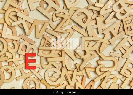 Ein roter Buchstabe unter hölzernen Buchstaben auf hellem Hintergrund. Das Konzept der Einzigartigkeit Stockfoto