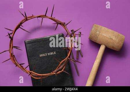 Dornenkrone mit Bibel, Hammer und Nägeln auf lila Hintergrund Stockfoto