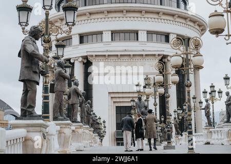 Touristen erkunden historische Statuen auf dem städtischen Platz mit kunstvollen Laternenpfählern. Stockfoto