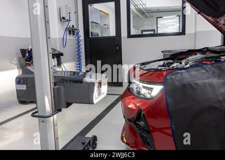 Scheinwerfereinstellung des Fahrzeugs im Autoservice. Der Mitarbeiter einer Autowerkstatt überprüft und stellt die Scheinwerfer der Fahrzeugbeleuchtung ein. Stockfoto