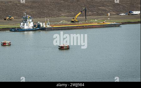 Panamakanal, Panama - 24. Juli 2023: Culebra Schlepper und Lastkahn mit Schmutz zur Verstärkung der Küste. Planierschild und Kran, die die harte Arbeit erledigen. Stockfoto