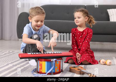 Kleine Kinder, die zu Hause Spielzeugmusikinstrumente spielen Stockfoto