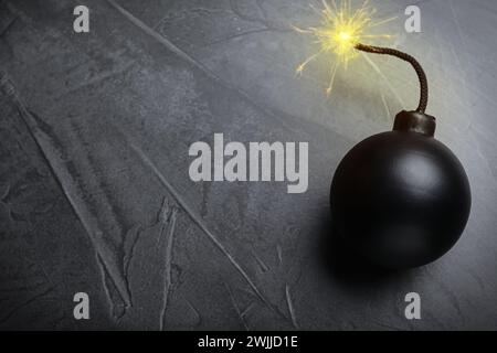 Altmodische schwarze Bombe mit beleuchteter Sicherung auf grauem Tisch, Draufsicht. Leerzeichen für Text Stockfoto
