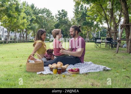 Eine Familie genießt gemeinsam Essen auf einer Decke, Picknick im Park. Stockfoto