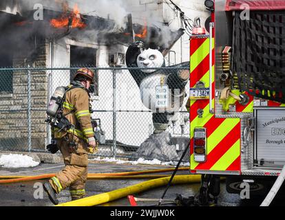 Edwardsville, Usa. Februar 2024. Ein Feuerwehrmann geht an einer Kung Fu Panda Statue vor einem MMA Studio neben dem Dancheck Feuerlöschergebäude vorbei. Ein Feuer mit zwei Alarmen brach am Donnerstag durch die Dancheck Feuerlöschfabrik. Viele Abteilungen kamen, um den Brand zu löschen, wo Wasser ein Problem war. Das Gebäude war ein Totalschaden. Quelle: SOPA Images Limited/Alamy Live News Stockfoto