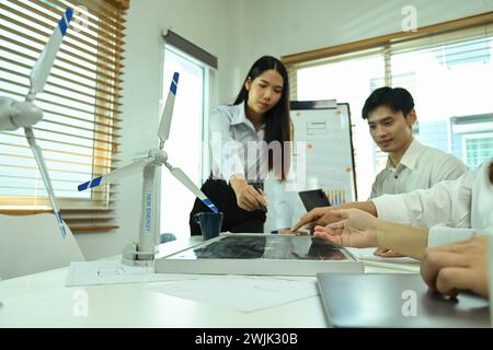 Team von Öko-Ingenieuren, die im Büro mit Windkraftanlagenmodellen und Solarpaneelen arbeiten Stockfoto