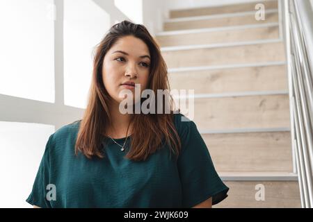 Junge birassische Frau in Übergröße steht nachdenklich drinnen, mit unverändertem Kopierraum Stockfoto