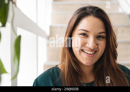 Eine junge Frau in Übergröße lächelt drinnen herzlich, mit unverändertem Kopierraum Stockfoto