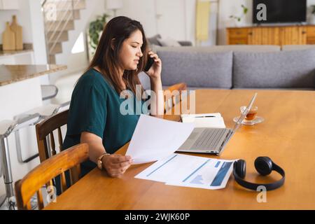 Eine junge Frau in Übergröße arbeitet von zu Hause aus und überprüft Dokumente unverändert Stockfoto