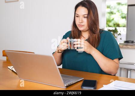 Eine junge Frau in Übergröße arbeitet von zu Hause aus und trinkt unveränderten Kaffee Stockfoto