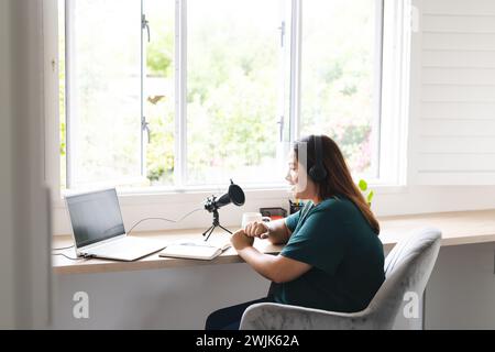 Junge birassische und große Frau nimmt zu Hause einen Podcast auf, mit unverändertem Kopierraum Stockfoto