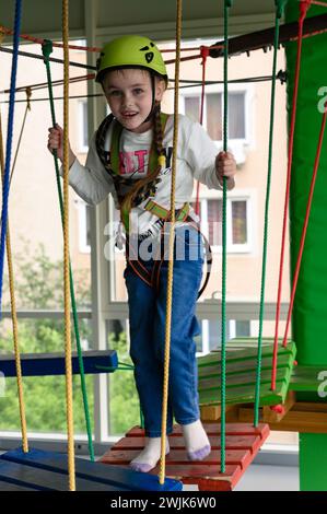 Kinderseilbahn im Spielzimmer passiert das kleine Mädchen die Seilbahn, die aktive und körperliche Entwicklung des Kindes. Stockfoto