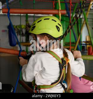 Aktive und körperliche Entwicklung des Kindes, das Mädchen passiert die Seilbahn im Spielzimmer. Stockfoto