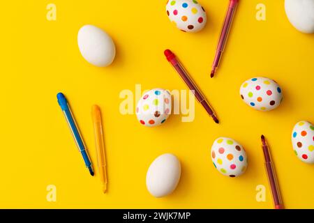 Bunte ostereier mit Filzstiften auf gelbem Hintergrund. Direkt über der Tischplatte. Stockfoto