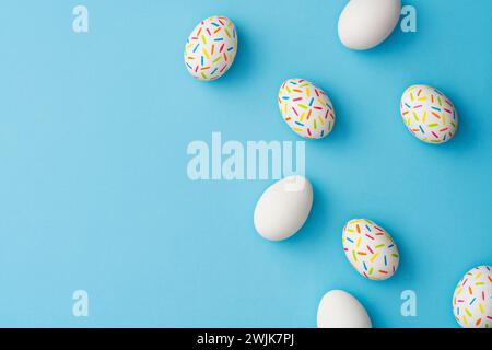 Bestreuen Sie bunte ostereier auf blauem Hintergrund. Direkt über der Tischplatte. Stockfoto