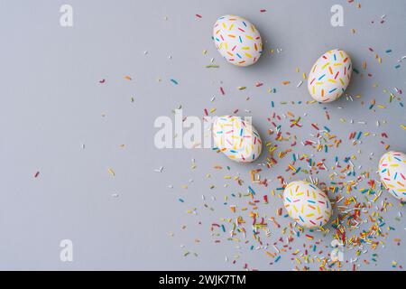 Bestreuen Sie farbenfrohe ostereier auf grauem Hintergrund. Direkt über der Tischplatte. Stockfoto