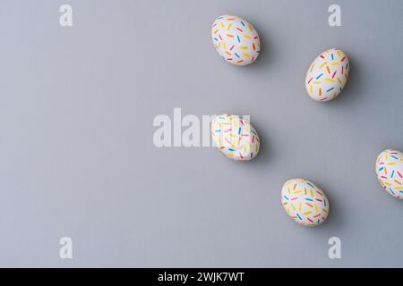Bestreuen Sie farbenfrohe ostereier auf grauem Hintergrund. Direkt über der Tischplatte. Stockfoto