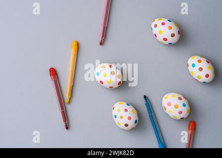 Bunte ostereier mit Farbstiften auf grauem Hintergrund. Direkt über der Tischplatte. Stockfoto