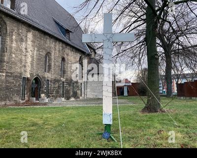 16. Februar 2024, Thüringen, Mühlhausen: Vor der Jugendkirche in Mühlhausen steht ein Kreuz, das Anfang April 2023 zum Gedenken an die Toten eines Autounfalls bei Bad Langensalza in Thüringen aufgestellt wurde. Die Klageschrift und das Urteil werden am Freitag vor dem Amtsgericht Mühlhausen in der Verhandlung um einen Autounfall bei einem Horrorunfall erwartet, bei dem sieben Menschen ums Leben kamen. Die Staatsanwaltschaft wirft dem Angeklagten vor, das Auto zu fahren, das den Unfall verursacht hat, während er betrunken und zu schnell war. Er hatte auch keinen Führerschein. Der 35-Jährige wird wegen sieben unfreiwilligen M angeklagt Stockfoto