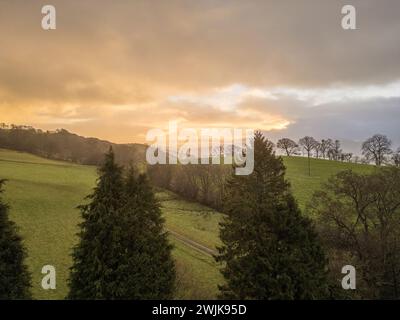 Sonnenaufgang über den Hügeln von Denbighshire, Wales, wenn die Sonne durch dunkle Wolken bricht und leichter Regen über die Landschaft fällt. Stockfoto