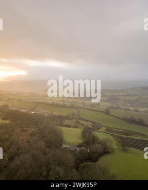 Sonnenaufgang über den Hügeln von Denbighshire, Wales, wenn die Sonne durch dunkle Wolken bricht und leichter Regen über die Landschaft fällt. Stockfoto