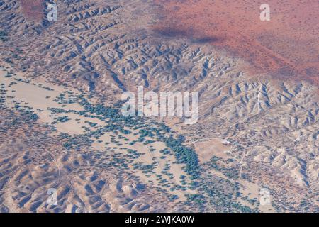 Luftlandschaft mit kleiner Farm und karger Vegetation im trockenen Fluss Nossob in der Kalahari Wüste, aufgenommen von einem Segelflugzeug in hellen späten Frühlingslichtern Stockfoto