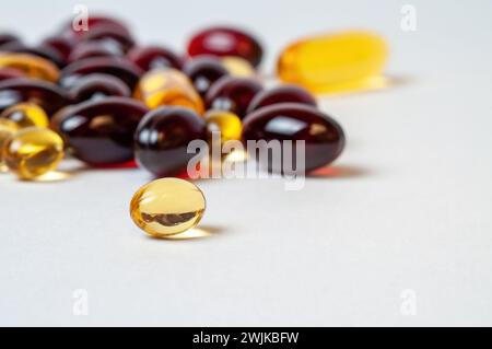 Verschiedene Nahrungsergänzungsmittel auf einer weißen Oberfläche, glänzende Pillen verstreut auf einem sauberen. Stockfoto